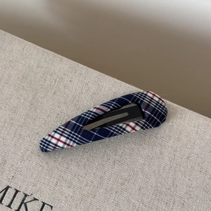 Detail of plaid fabric hair clip featuring classic blue and red Scottish tartan texture