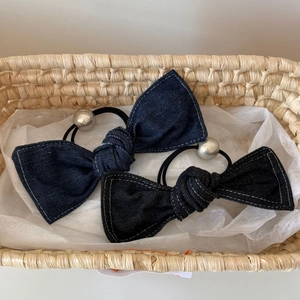 Close-up of denim bow hair scrunchies with metallic beads in a woven basket