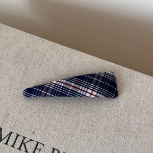 Close-up of a blue and red plaid fabric BB hair clip on a textured display box