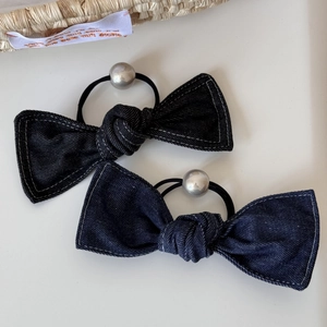 Detailed macro view of denim blue bow hair ties with white stitching and silver beads