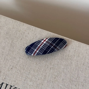 Close-up of navy blue and red plaid fabric texture on an oval BB hair clip for women