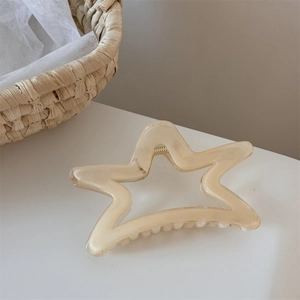 Détail d'une pince à cheveux étoile beige translucide avec ressort en métal doré