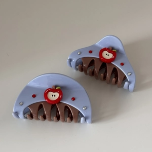 Detail view of lavender resin hair claw with a red apple motif and sparkling rhinestones