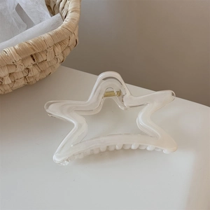 Détail d'une pince à cheveux étoile avec texture marbrée crème sur une table blanche