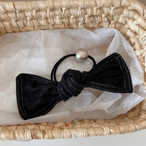 Detail of denim bow hair scrunchie with white contrast stitching and silver bead accent