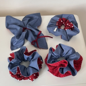 Detail of four handmade scrunchies in denim blue and red polka dot fabric with labels