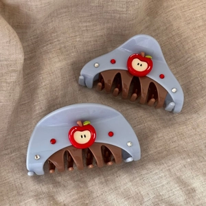 Detail of light blue hair claws with red apple motif and sparkling rhinestones