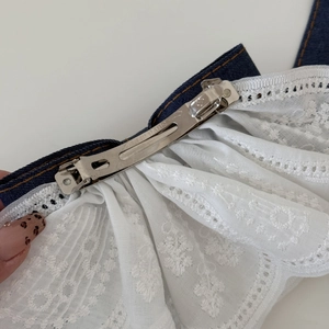 Detail of denim bow hair clip with white lace trim and silver metal barrette spring
