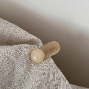 Λήψη macro μπεζ κλιπ μαλλιών με χάραξη France Handmade πάνω σε φυσικό υφασμάτινο φόντο