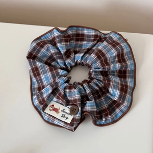 Détail du chouchou à carreaux bleu et marron avec étiquette chien et bouton décoratif