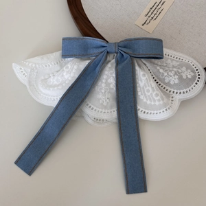 Detail showing white lace embroidery texture and blue denim bow on a vintage hair clip