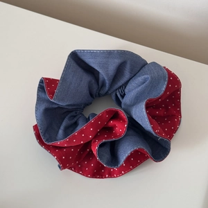 Detailed view of dual-sided hair scrunchie with denim blue fabric and red polka dots