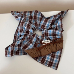 Gros plan sur chouchou à carreaux bleu et marron avec nœud et étiquette de marque