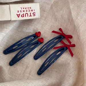 Quatre barrettes bleu marine avec cœurs rouges et nœuds en velours sur fond de lin