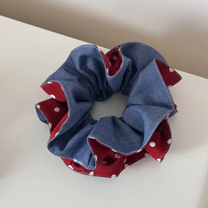 Detail of blue denim and red polka dot fabric scrunchie with stitching texture