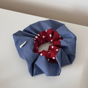 Close-up of denim blue and red polka dot scrunchie with white woven fabric label