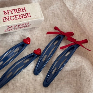 Détail de barrettes bleu marine avec cœurs rouges et nœuds en ruban sur lin beige