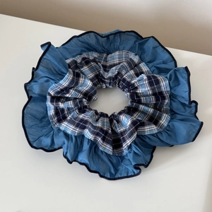 Détail d'un chouchou à carreaux bleus avec bordure plissée translucide superposée