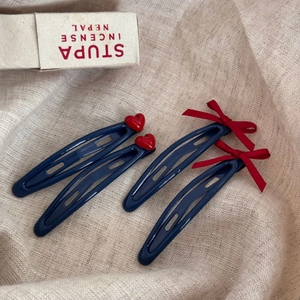 Lot de quatre barrettes bleu marine avec cœurs rouges et nœuds sur tissu beige naturel
