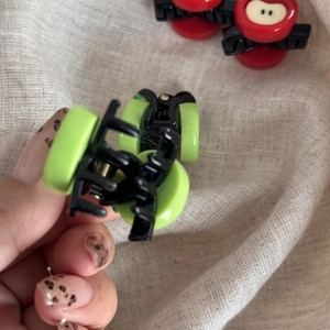 Close-up of mini red and green apple hair claws with shiny finish and black metal spring