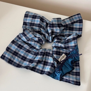 Vue détaillée d'un chouchou à carreaux bleu et noir avec bordure en dentelle et lacets