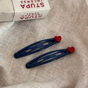 Gros plan de barrettes bleues marine avec détail cœur rouge brillant sur tissu en lin