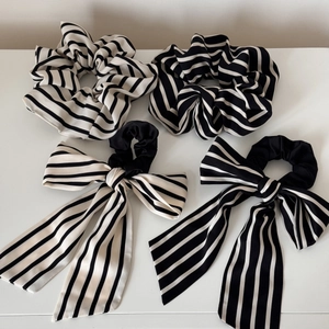 Detail of four black and white striped hair scrunchies with long ribbons on white surface