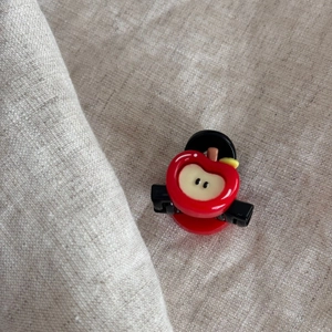 Close-up of mini red apple hair claw clip showing polished texture on linen fabric