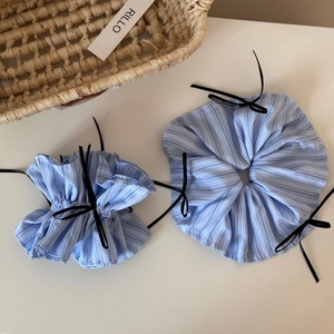 Blue striped scrunchies with black ribbons on a minimalist aesthetic background
