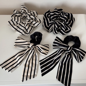 Detail view of a four-piece black and white striped scrunchie set with ribbon bows