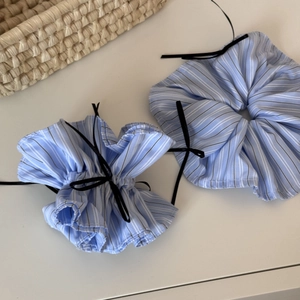 Close-up of blue striped scrunchie with black bow detail on a woven background