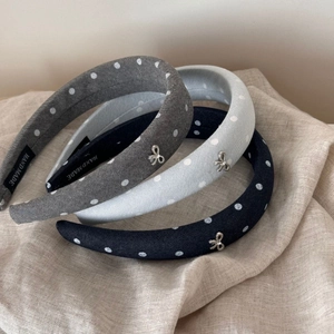 Set of three polka dot fabric headbands with silver bows on a textured linen background