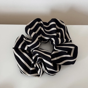 Macro view of black and white striped fabric scrunchie with soft pleated texture