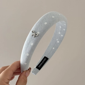 Detailed macro view of polka dot sponge headband with silver bow and handmade label