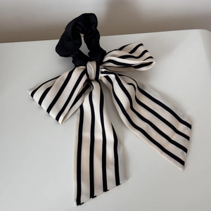 Detail of black and white striped long ribbon hair tie with a soft bow design