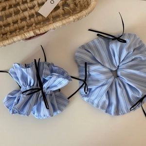 Detail of blue striped scrunchies with black bows on a minimalist white table
