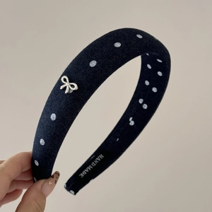 Close-up of black polka dot sponge headband with silver bow detail and handmade label