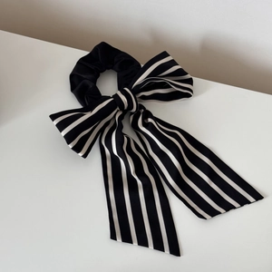 Detail of high-quality satin striped bow scrunchie with long ribbons and smooth texture