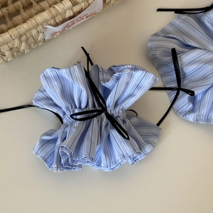 Detail of blue striped scrunchie with a delicate black ribbon bow on white background