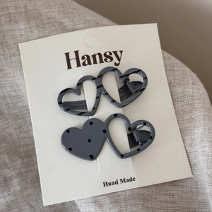 Detail view of two heart-shaped hair clips with polka dots and stripes on a display card