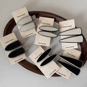 Gros plan de pinces à cheveux minimalistes noir et blanc sur emballage élégant en papier