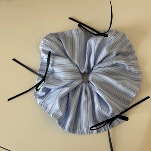 Detail of blue striped scrunchie with delicate black bows on soft beige background