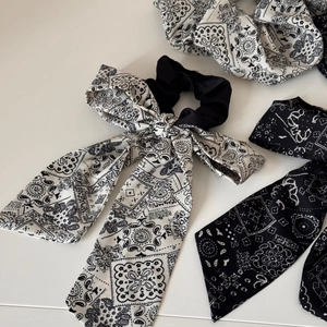 Detailed view of paisley bow hair ties in black and white matte fabric textures