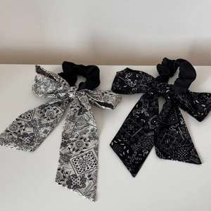 Detail of two bandana paisley bow hair scrunchies in classic black and white patterns