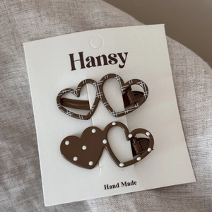 Close-up of heart-shaped hair clips with polka dots and grid patterns on a card