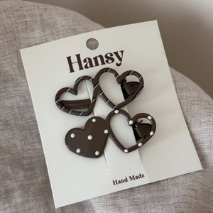 Close-up of heart-shaped hair clips with white polka dots and stripes on display card