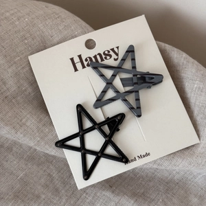 Close-up of star-shaped duckbill hair clips in black and grey patterns on a display card