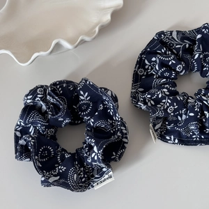 Navy blue floral scrunchie set with white botanical patterns and woven logo label