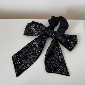 Detail of a black paisley print scrunchie bow with elegant floral patterns on chiffon fabric