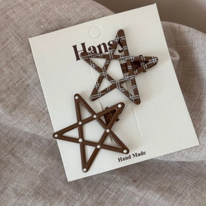 Close-up of two star-shaped hair clips with polka dots and checks on card packaging